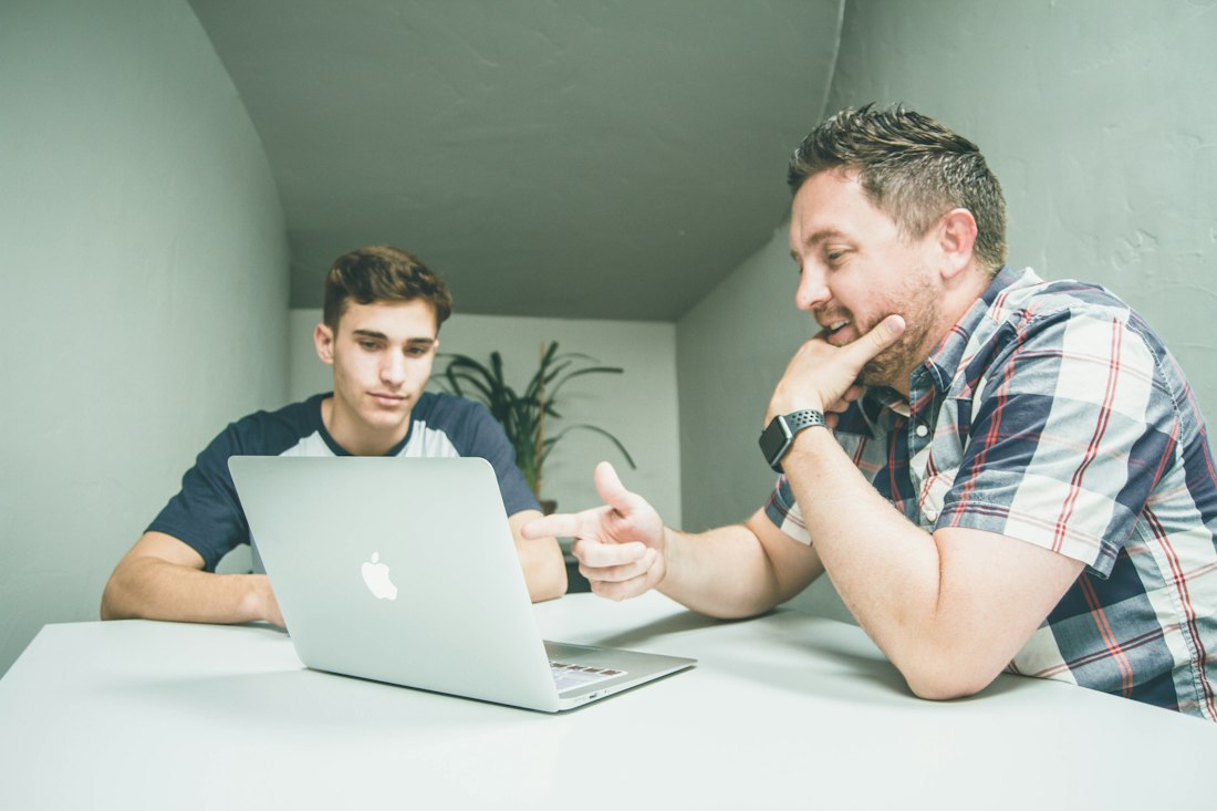 Two colleagues discussing figures on a laptop
