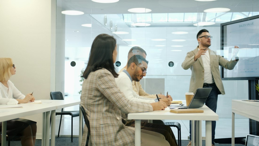 Mentor presenting to colleagues in a modern meeting room