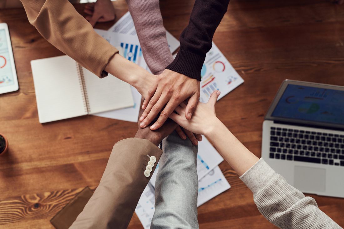 Team members stacking hands together as a sign of commitment