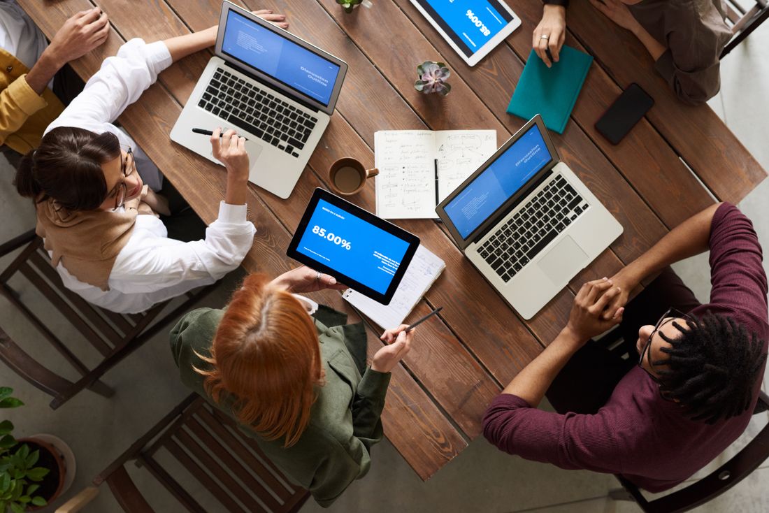 Team members working on laptops around a table seen from above